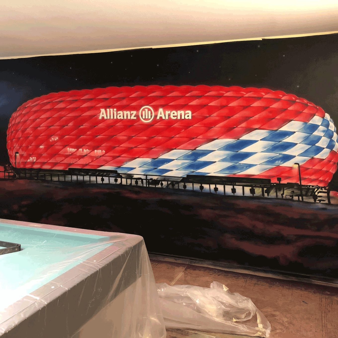 wandgestaltung mit allianz arena im partykeller, billiardraum, detailreich gemaltes fußballstadion mit roter beleuchtung, individuell in münster gestaltet
